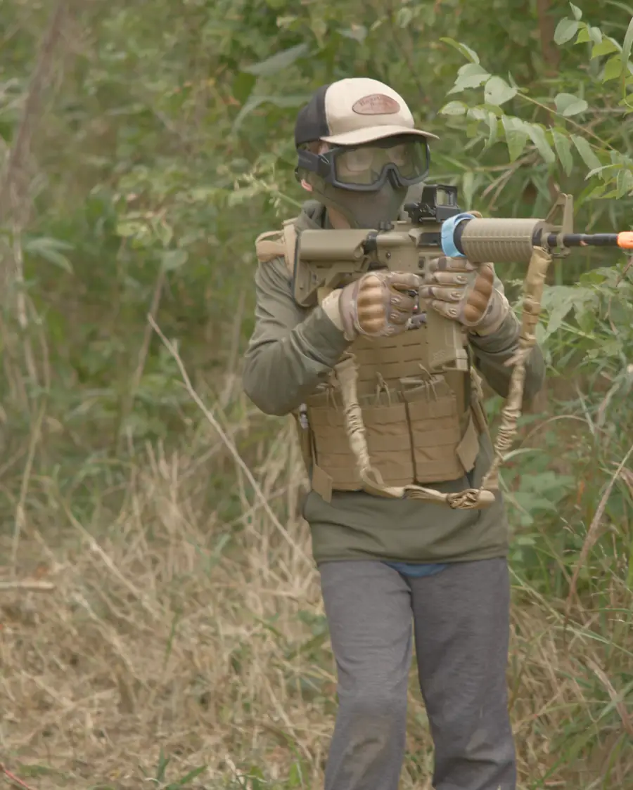A player fires from cover in tall grass